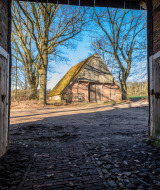 Vista a través de una puerta de granero abierta hacia una construcción tradicional en un parque de glamping.