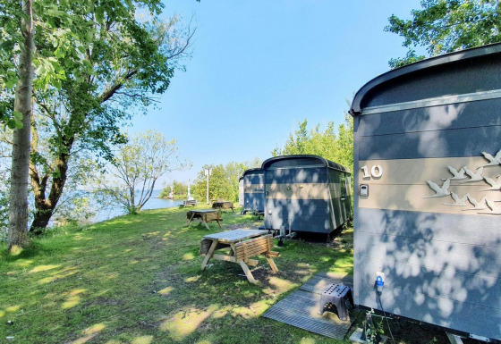Casas Tiny Wagon en Marina Parcs Almere, Países Bajos, rodeadas de árboles y mesas de picnic al aire libre.