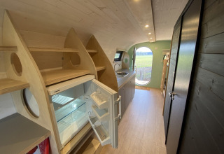 Binnenkant van een modern vakantiehuisje met open koelkast en kitchenette in Holiday Park 't Rheezerwold.