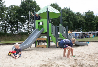 Kinderen spelen in de zandbak en op de glijbaan op de speeltuin van vakantiepark 't Rheezerwold, Overijssel.