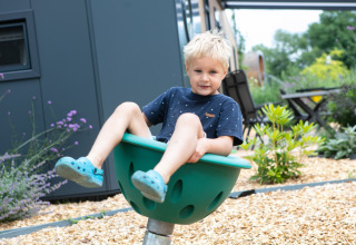 Jonge jongen speelt buiten op een groene draaischijf bij vakantiepark 't Rheezerwold in Overijssel, Nederland.