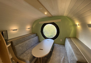 Interiør af en moderne feriebolig med runde vinduer og sofaer i Holiday Park 't Rheezerwold, Overijssel.