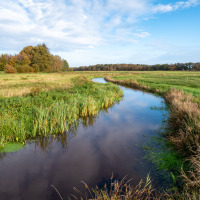Río serpenteando por praderas verdes cerca de un parque vacacional con alojamientos glamping.