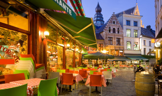 Ambiente nocturno en terraza de restaurante europeo con sillas de colores y calles adoquinadas pintorescas.