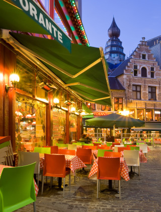 Avondsfeer op een gezellig terras van een Europees restaurant met kleurrijke stoelen en kasseistraten.