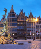 Vista nocturna de la Grote Markt de Amberes con la fuente Brabo y casas gremiales históricas.