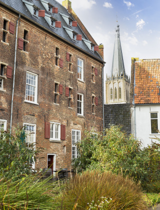 Edificio histórico de ladrillo con contraventanas rojas y torre de iglesia en Zelhem, Gelderland, Países Bajos.