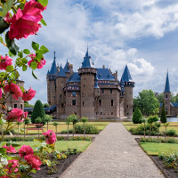 Hermoso castillo con torres, rodeado de rosales y jardines verdes, en un parque vacacional con glamping.