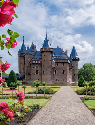 Prachtig kasteel met torentjes, omgeven door bloeiende rozen en tuinen op een glamping vakantiepark.