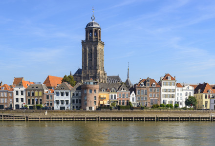 Scenic view of a Dutch riverside town with a prominent church tower and colorful historic houses in Holland.