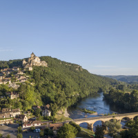 Foto de un pueblo en la ladera, castillo medieval y puente cerca de un parque vacacional con glamping.