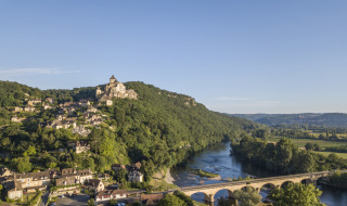 Foto de un pueblo en la ladera, castillo medieval y puente cerca de un parque vacacional con glamping.