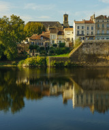 Vista pintoresca de un pueblo junto al río y puente desde un parque vacacional con opciones de glamping.