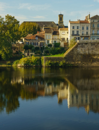 Vista pintoresca de un pueblo junto al río y puente desde un parque vacacional con opciones de glamping.