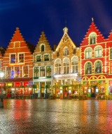 Casas de colores con gabletes iluminados en Westende, Flandes Occidental, Bélgica, reflejadas en adoquines mojados.