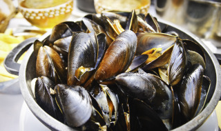 Una olla con mejillones al vapor servidos en una mesa en un parque vacacional de alojamiento glamping.