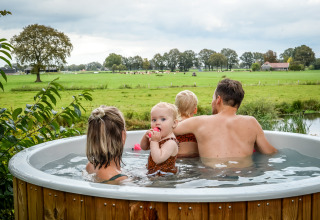 Familie slapper af i et vildmarksbad med udsigt over grønne marker i Holiday Park Mölke, Overijssel.