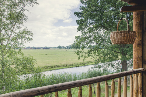 Blick von einem Balkon im Holiday Park Mölke, Overijssel, Niederlande auf grünes Feld mit Korb.