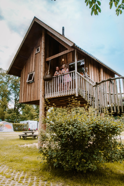 Træhytte med balkon i Holiday Park Mölke, Overijssel, Holland, med mennesker stående på altanen.