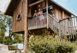 Casetta sull'albero con balcone al Holiday Park Mölke, Overijssel, Paesi Bassi, con persone sul balcone.