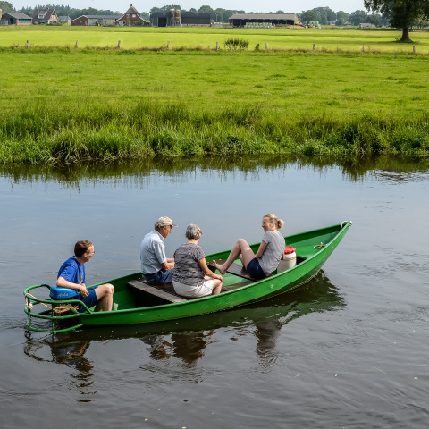 Vier Personen fahren in einem grünen Boot auf einem Fluss im Holiday Park Mölke, Overijssel, Niederlande.