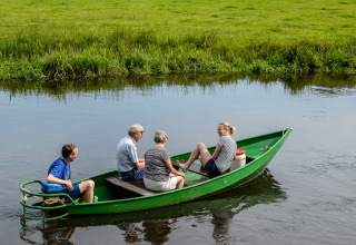 Vier Personen fahren in einem grünen Boot auf einem Fluss im Holiday Park Mölke, Overijssel, Niederlande.