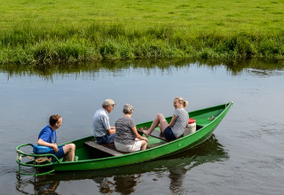 Vier mensen genieten van een boottocht op de rivier bij Vakantiepark Mölke in Overijssel, Nederland.