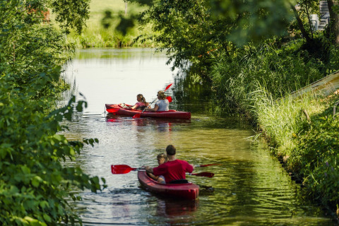Famiglie in kayak rossi su un canale verdeggiante al Holiday Park Mölke a Overijssel, Paesi Bassi.