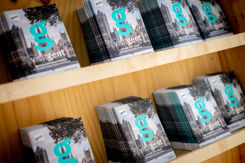 Stacks of 'visitgent' official city guides on shelves at Urban-Gardens holiday park in East Flanders, Belgium.
