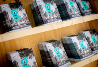 Stacks of 'visitgent' official city guides on shelves at Urban-Gardens holiday park in East Flanders, Belgium.