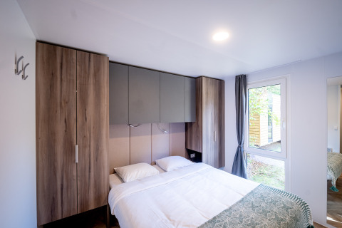 Moderne slaapkamer met dubbel bed, ingebouwde kasten en groot raam in Urban-Gardens, Oost-Vlaanderen.