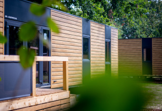 Contemporary wooden holiday lodges at Urban-Gardens park in East Flanders, Belgium, with lush greenery.