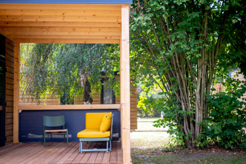Holzterrasse mit farbenfrohen Stühlen und grünem Garten im Urban-Gardens Ferienpark, Ostflandern.