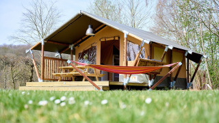 Tienda safari llamada Villatent Compact con hamaca en Camping 't Geuldal, Países Bajos, en primavera.