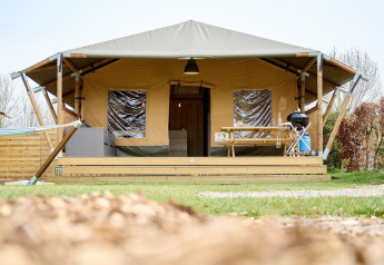 Tienda safari Villatent Cottage en Camping 't Geuldal, Países Bajos, con terraza, mesa y barbacoa fuera.