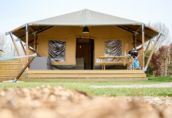 Tienda safari Villatent Cottage en Camping 't Geuldal, Países Bajos, con terraza, mesa y barbacoa fuera.