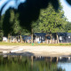 Strandhuse ved Camping 't Veld i Holland, med sø, træer, og mennesker der nyder naturen.