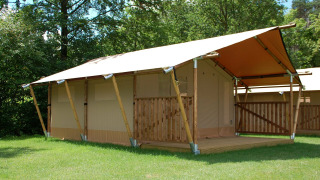 Safari tent at Baalse Hei in Belgium featuring a wooden frame and covered porch, surrounded by greenery.