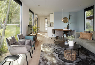 Modern interieur van de Water Cube lodge met grote ramen, stijlvolle meubels en uitzicht op tuin.
