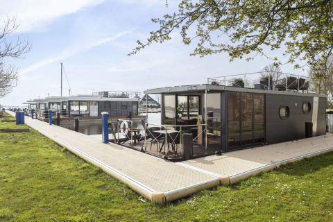 Moderno barco-casa 'Iere Fügel' atracado en Welcome In - Friesland, Países Bajos, junto al muelle.