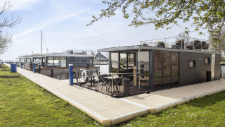 Moderno barco-casa 'Iere Fügel' atracado en Welcome In - Friesland, Países Bajos, junto al muelle.