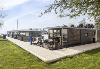 Moderno barco-casa 'Iere Fügel' atracado en Welcome In - Friesland, Países Bajos, junto al muelle.