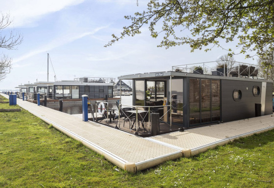 Moderno barco-casa 'Iere Fügel' atracado en Welcome In - Friesland, Países Bajos, junto al muelle.