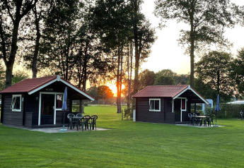 Due accoglienti chalet con patio e mobili da giardino al tramonto nel Recreation Park Den Blanken, Olanda.