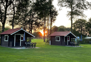 Dos acogedoras cabañas con terraza y muebles de jardín al atardecer en Recreation Park Den Blanken, Países Bajos.