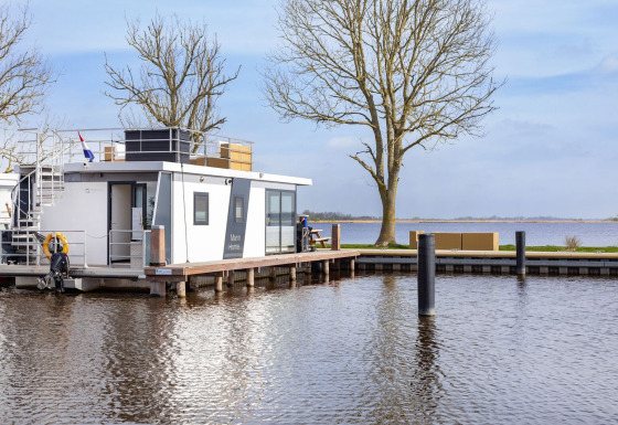Houseboat Aqua Dolce al Welcome In - Friesland, Paesi Bassi, ormeggiata sull’acqua con terrazza.