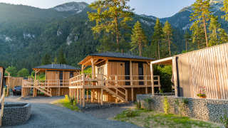 Cabanes en bois du lodge Edelweiss en montagne, entourées d’arbres et d’un paysage verdoyant paisible.