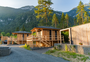 Cabanes en bois du lodge Edelweiss en montagne, entourées d’arbres et d’un paysage verdoyant paisible.