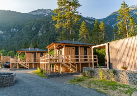 Houten hutten bij Edelweiss Lodge in de bergen, omringd door bomen en een groene, natuurlijke omgeving.
