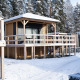 Houten lodges bij de besneeuwde Edelweiss lodge met glazen ramen, terras en bos op de achtergrond.